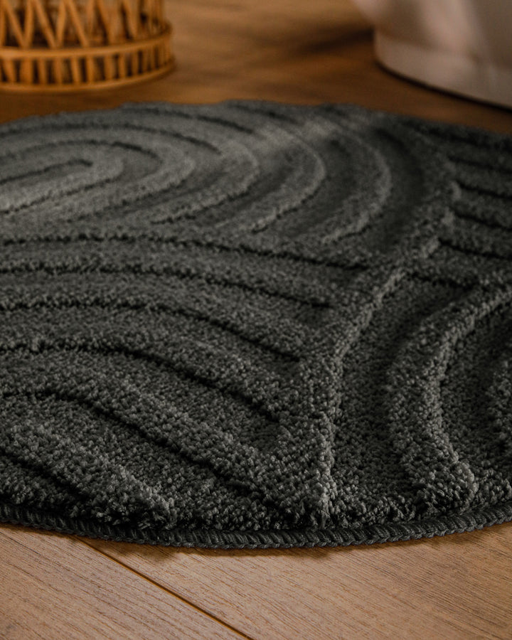Badteppich Fiete Anthrazit Grau rund im Badezimmer auf Holzboden neben Badewanne, Florstruktur und Linienrelief erkennbar