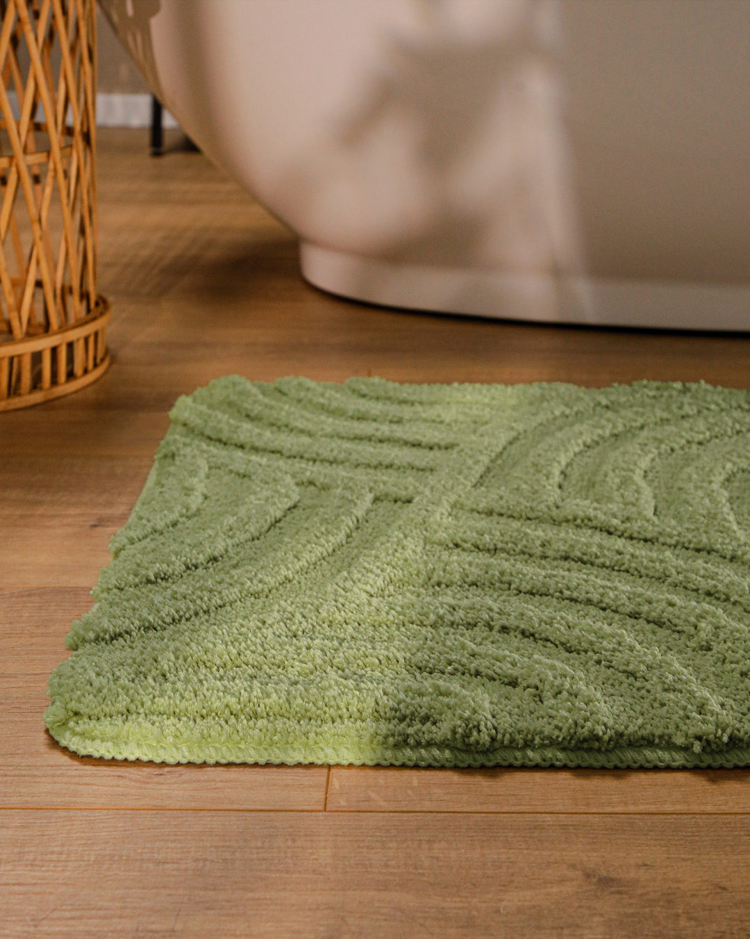 Badteppich Fiete Reseda Grün runde Matte im Badezimmer vor Badewanne, Strukturmuster im Flor auf Holzboden sichtbar