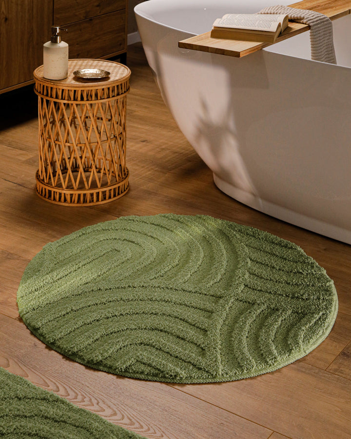Runder Badteppich Fiete Reseda Grün im Badezimmer vor Badewanne auf Holzboden, strukturiertes Linienrelief im Flor sichtbar