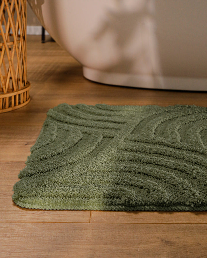 Badteppich Fiete Kiefer Grün runde Matte im Badezimmer vor Badewanne, Strukturmuster im Flor auf Holzboden sichtbar