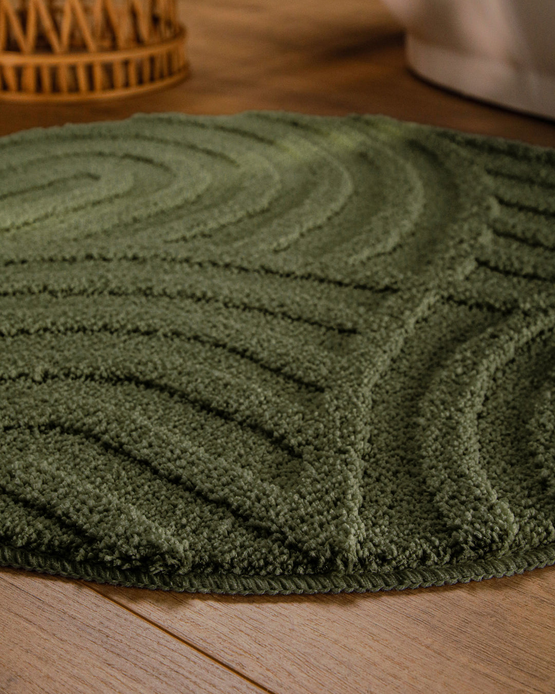 Badteppich Fiete Kiefer Grün rund im Badezimmer auf Holzboden neben Badewanne, Florstruktur und Linienrelief erkennbar