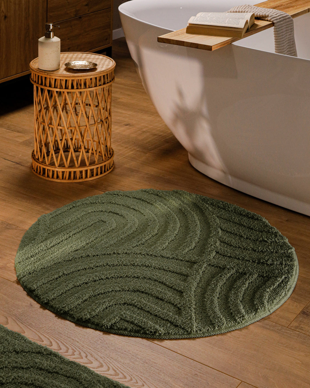 Runder Badteppich Fiete Kiefer Grün im Badezimmer vor Badewanne auf Holzboden, strukturiertes Linienrelief im Flor sichtbar
