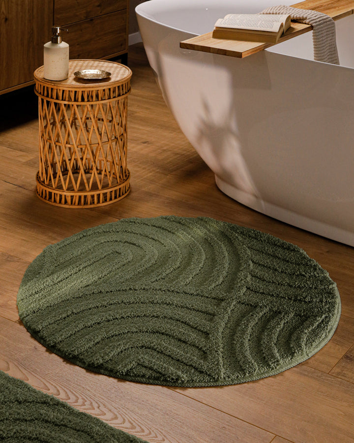 Runder Badteppich Fiete Kiefer Grün im Badezimmer vor Badewanne auf Holzboden, strukturiertes Linienrelief im Flor sichtbar