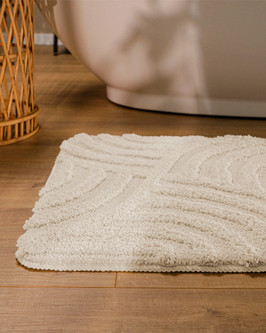 Badteppich Fiete Creme Weiß runde Matte im Badezimmer vor Badewanne, Strukturmuster im Flor auf Holzboden sichtbar