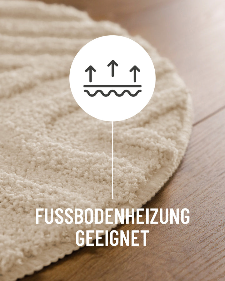 Badteppich Fiete Creme Weiß Detail der Teppichkante auf Holzboden, Symbol weist auf Eignung für Fußbodenheizung hin