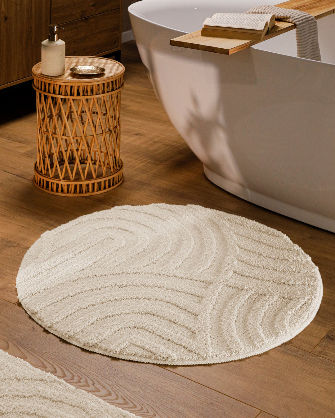 Runder Badteppich Fiete Creme Weiß im Badezimmer vor Badewanne auf Holzboden, strukturiertes Linienrelief im Flor sichtbar