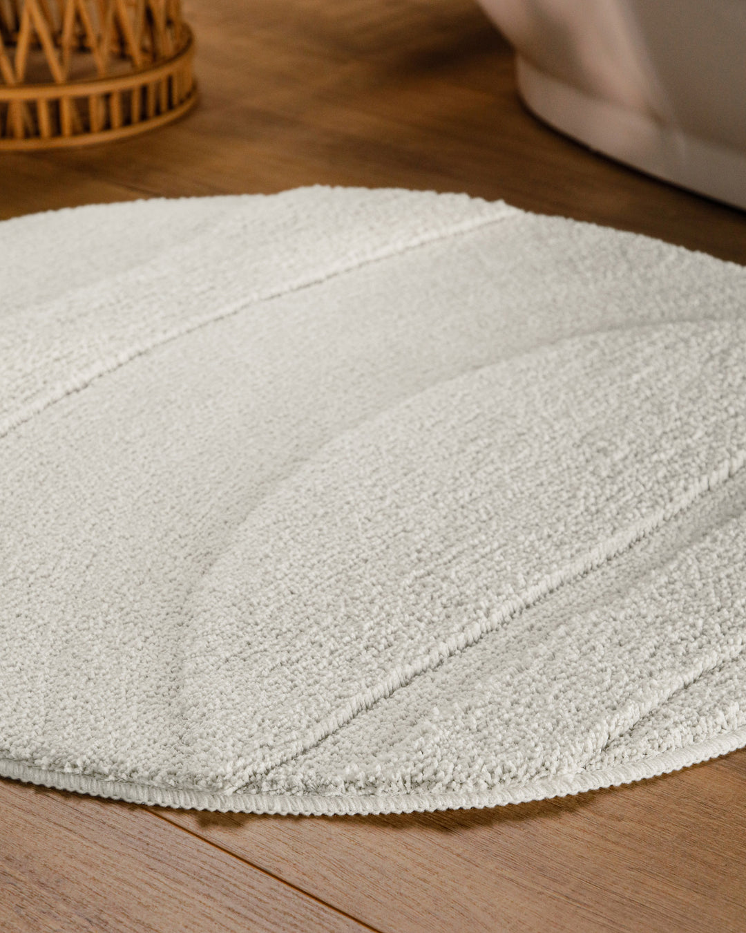 Badteppich Marc Weiß rund im Badezimmer auf Holzboden neben Badewanne, Florstruktur und Linienrelief erkennbar