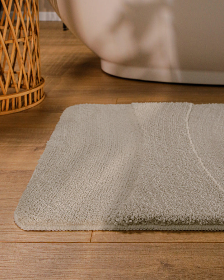 Badteppich Marc Grau runde Matte im Badezimmer vor Badewanne, Strukturmuster im Flor auf Holzboden sichtbar