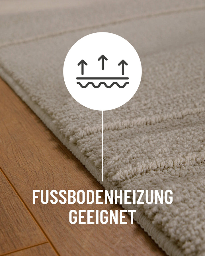 Badteppich Marc Grau Detail auf Holzfußboden mit Symbol für Fußbodenheizung, Nahaufnahme von Flor und Teppichkante
