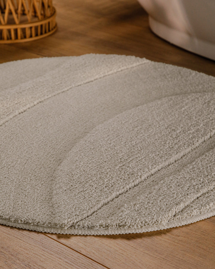 Badteppich Marc Grau rund im Badezimmer auf Holzboden neben Badewanne, Florstruktur und Linienrelief erkennbar