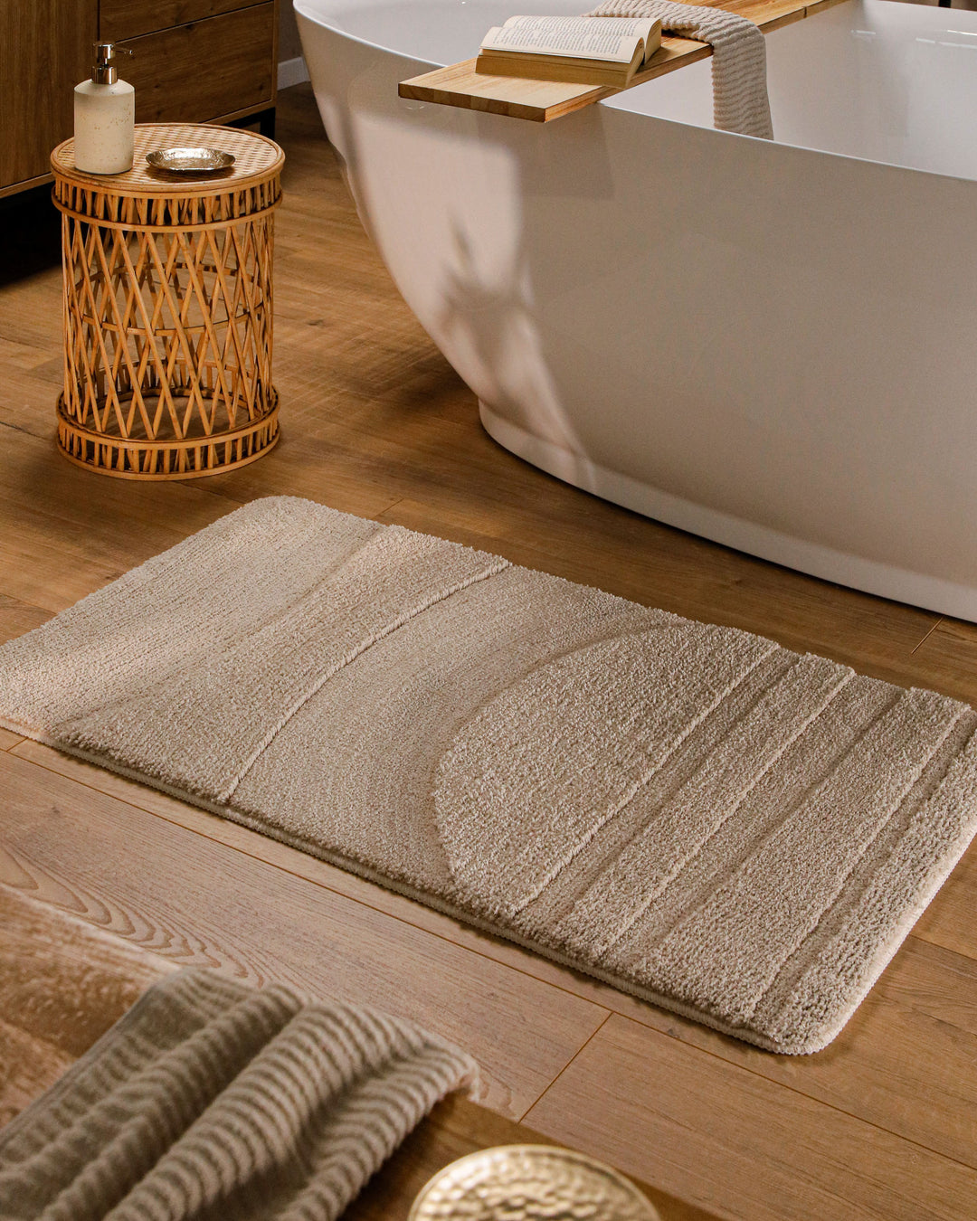 Badteppich Marc Sand Beige rechteckig im Badezimmer vor Badewanne auf Holzboden liegend, Strukturmuster im Flor sichtbar