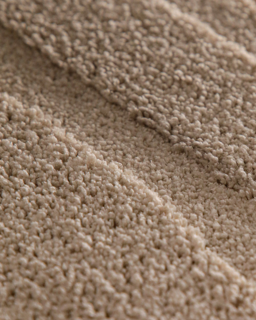 Badteppich Marc Sand Beige rund Detail der Teppichkante mit Hinweisen zu maschinengetufteter Verarbeitung