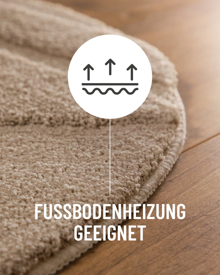 Badteppich Marc Sand Beige rund im Badezimmer auf Holzboden neben Badewanne, Florstruktur und Linienrelief erkennbar