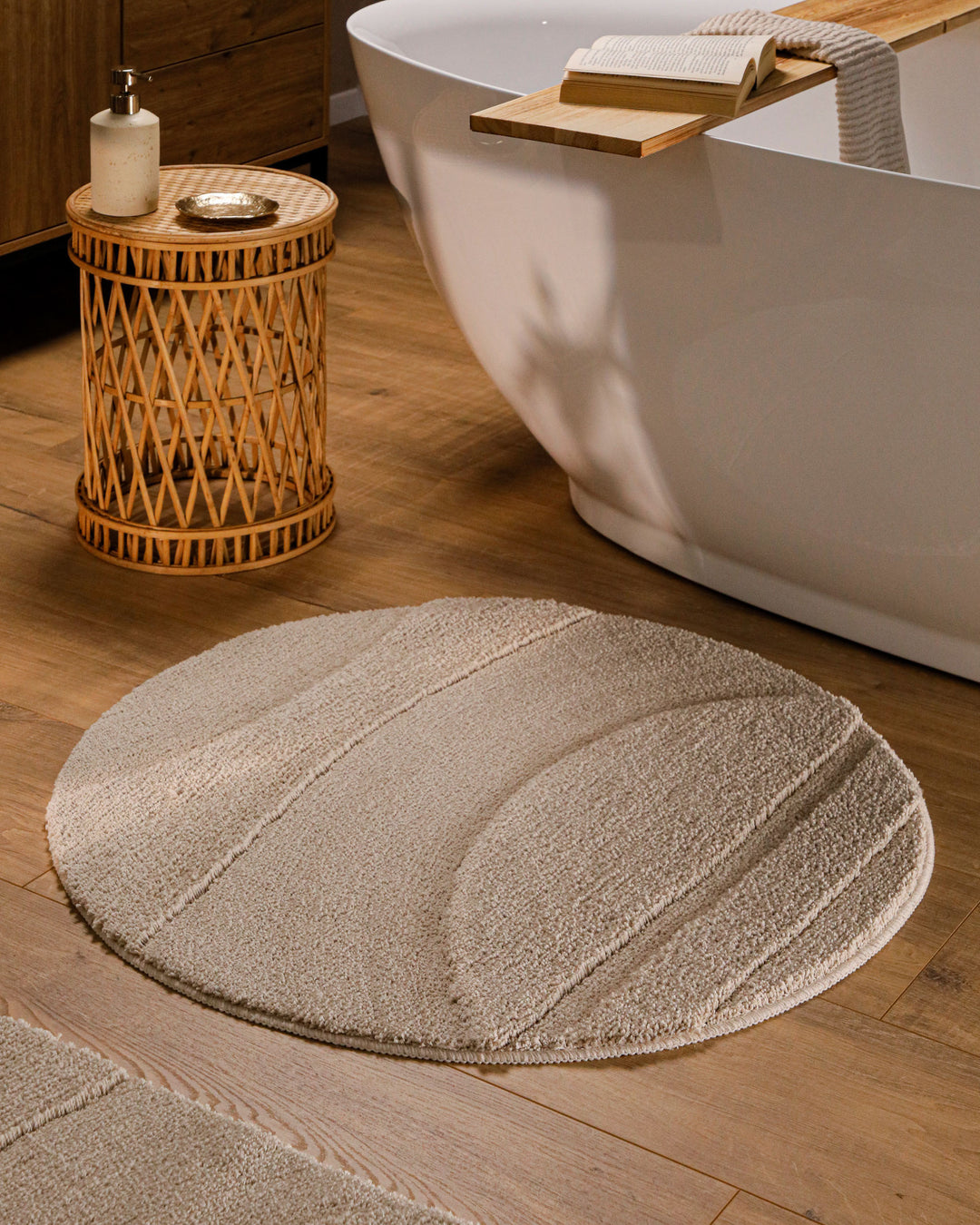 Badteppich Marc Sand Beige Detailaufnahme mit umgeschlagener Ecke, Hinweisgrafik zur rutschhemmenden Rückseite und Waschbarkeit