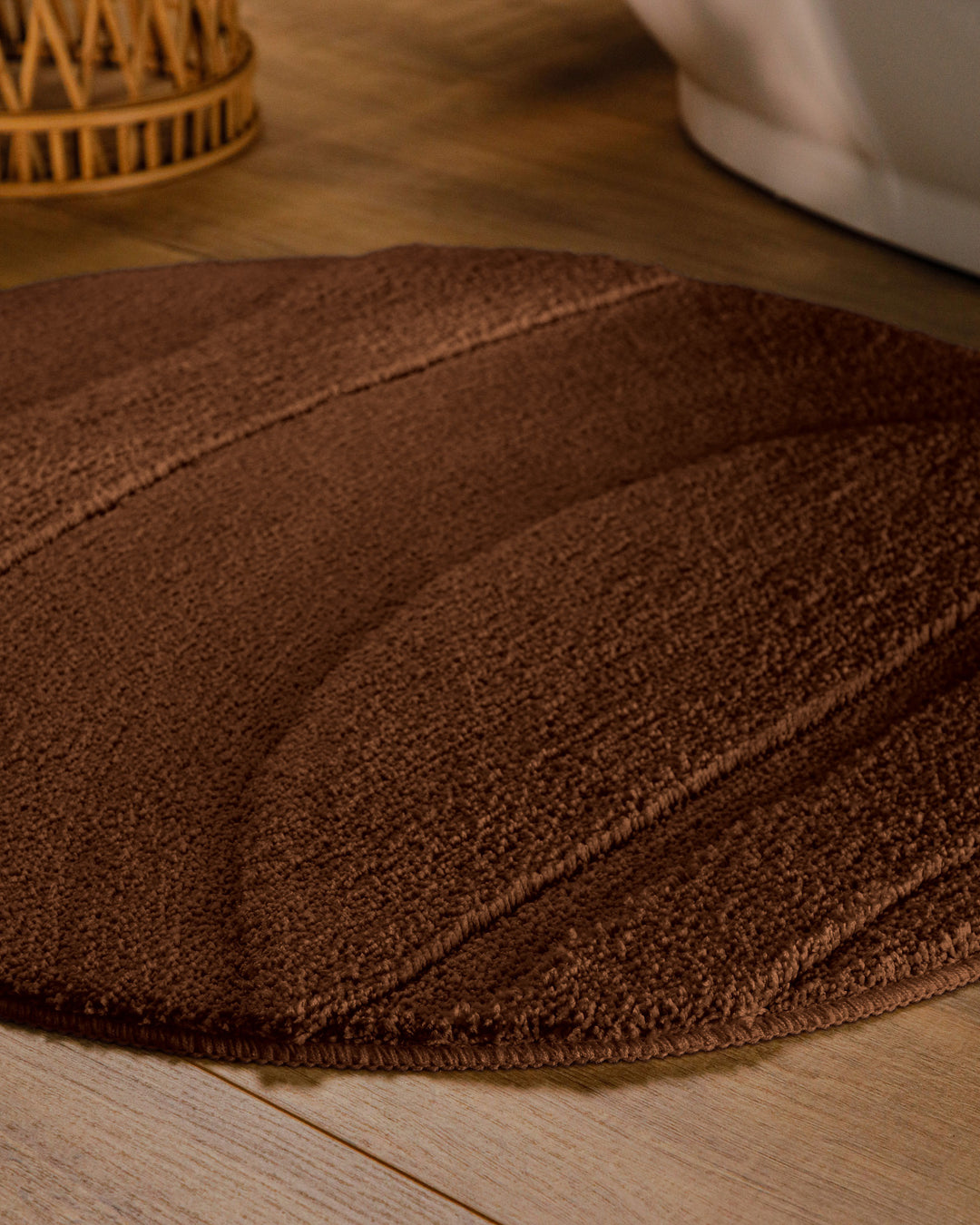 Badteppich Marc Braun rund im Badezimmer auf Holzboden neben Badewanne, Florstruktur und Linienrelief erkennbar