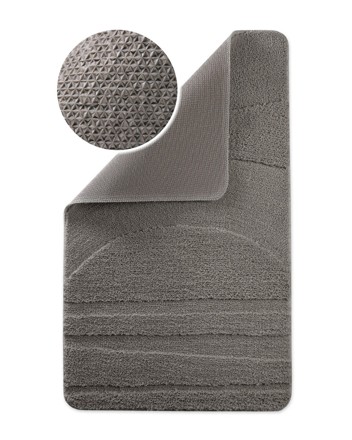 Badteppich Marc Basalt Grau Ecke hochgeklappt, runde Probe zeigt Basalt Graue Rückseite mit rutschhemmender Beschichtung
