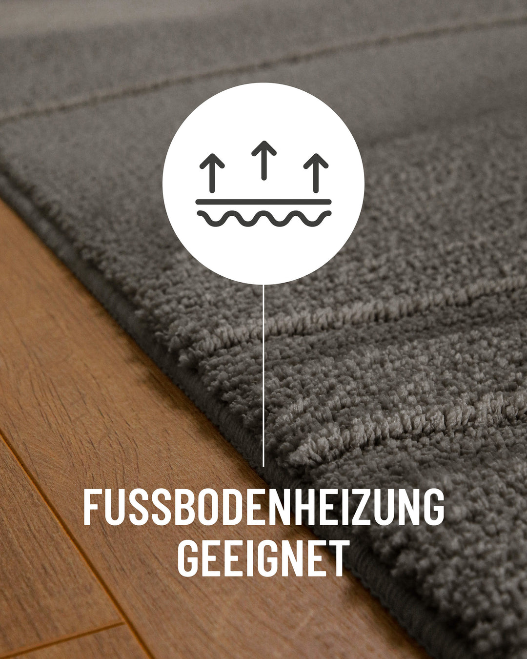 Badteppich Marc Basalt Grau Detail auf Holzfußboden mit Symbol für Fußbodenheizung, Nahaufnahme von Flor und Teppichkante