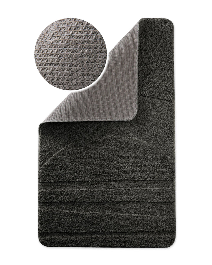 Badteppich Marc Anthrazit Grau Ecke hochgeklappt, runde Probe zeigt Anthrazit Graue Rückseite mit rutschhemmender Beschichtung