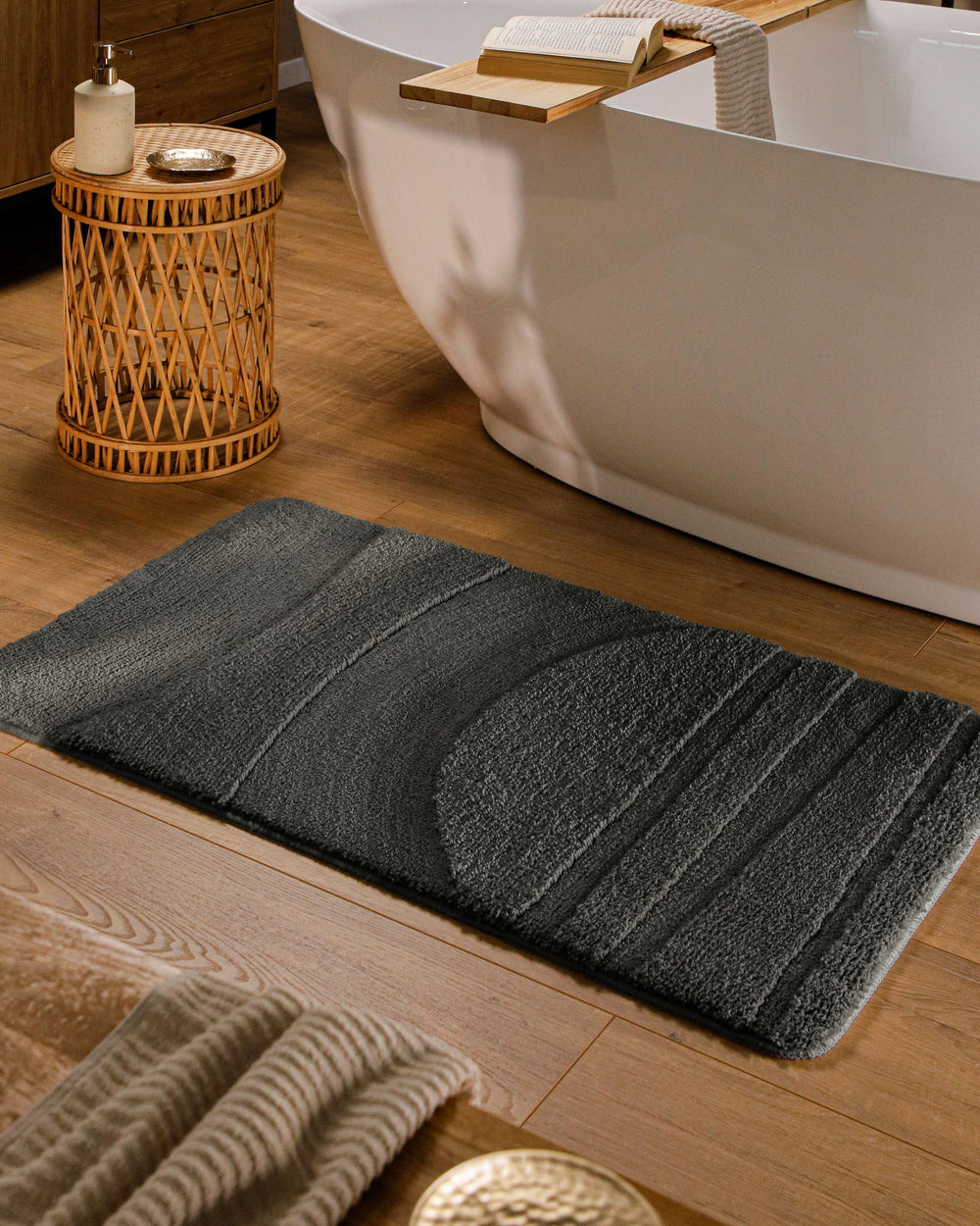 Badteppich Marc Anthrazit Grau rechteckig im Badezimmer vor Badewanne auf Holzboden liegend, Strukturmuster im Flor sichtbar