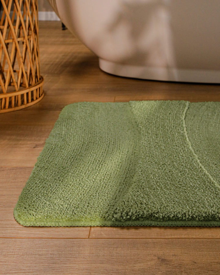 Badteppich Marc Reseda Grün runde Matte im Badezimmer vor Badewanne, Strukturmuster im Flor auf Holzboden sichtbar