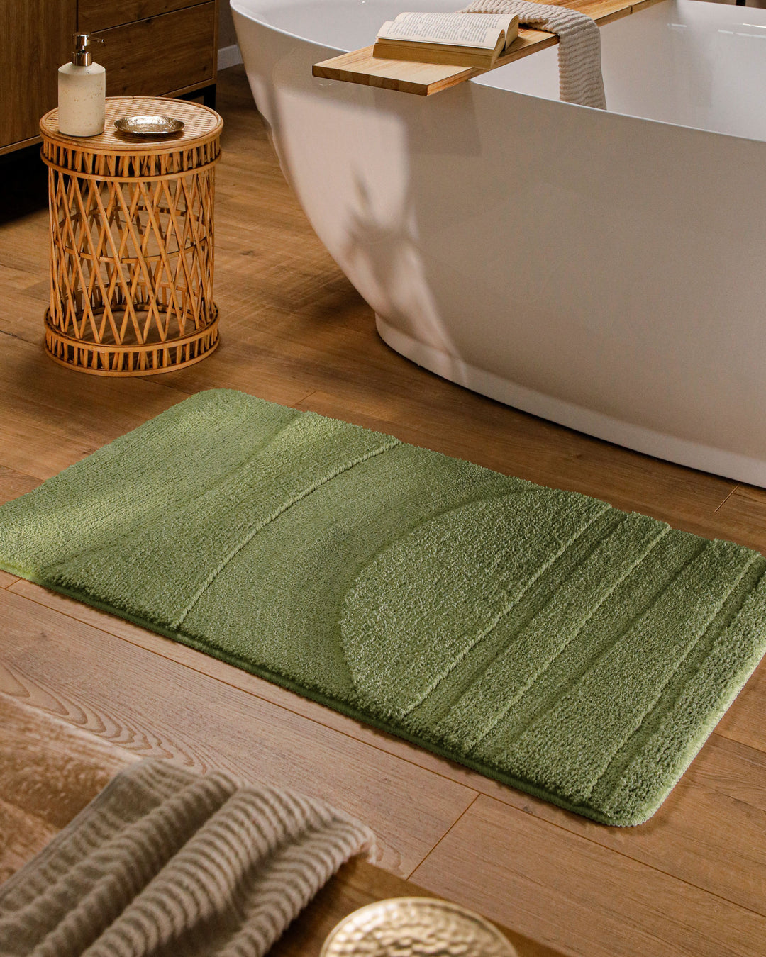 Badteppich Marc Reseda Grün rechteckig im Badezimmer vor Badewanne auf Holzboden liegend, Strukturmuster im Flor sichtbar