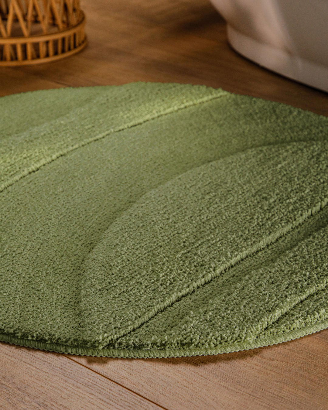 Badteppich Marc Reseda Grün rund im Badezimmer auf Holzboden neben Badewanne, Florstruktur und Linienrelief erkennbar