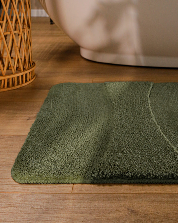 Badteppich Marc Kiefer Grün runde Matte im Badezimmer vor Badewanne, Strukturmuster im Flor auf Holzboden sichtbar