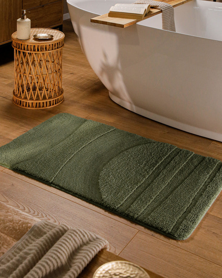 Badteppich Marc Kiefer Grün rechteckig im Badezimmer vor Badewanne auf Holzboden liegend, Strukturmuster im Flor sichtbar