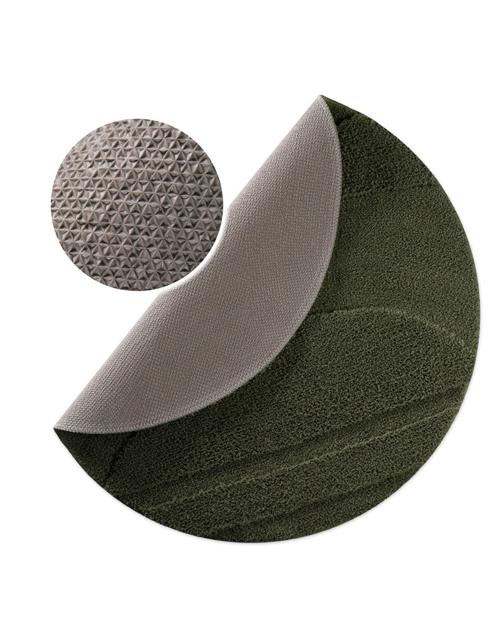 Badteppich Marc Kiefer Grün rund, angehobene Ecke zeigt Kiefer Grüne Rückseite mit rutschhemmender Beschichtung