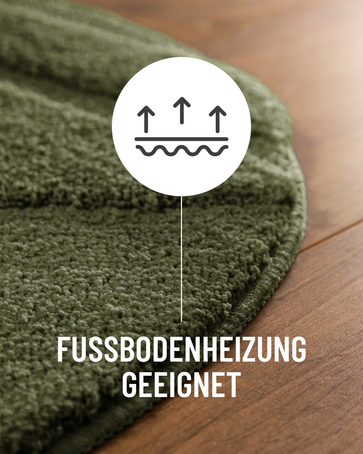 Badteppich Marc Kiefer Grün Detail der Teppichkante auf Holzboden, Symbol weist auf Eignung für Fußbodenheizung hin