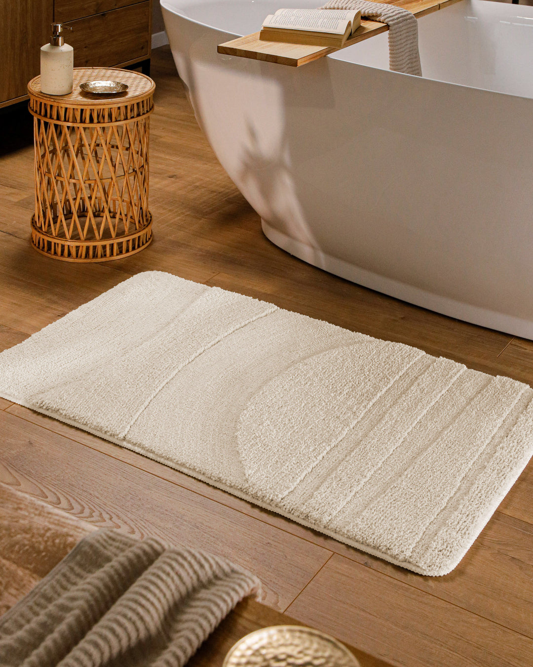 Badteppich Marc Creme Weiß rechteckig im Badezimmer vor Badewanne auf Holzboden liegend, Strukturmuster im Flor sichtbar