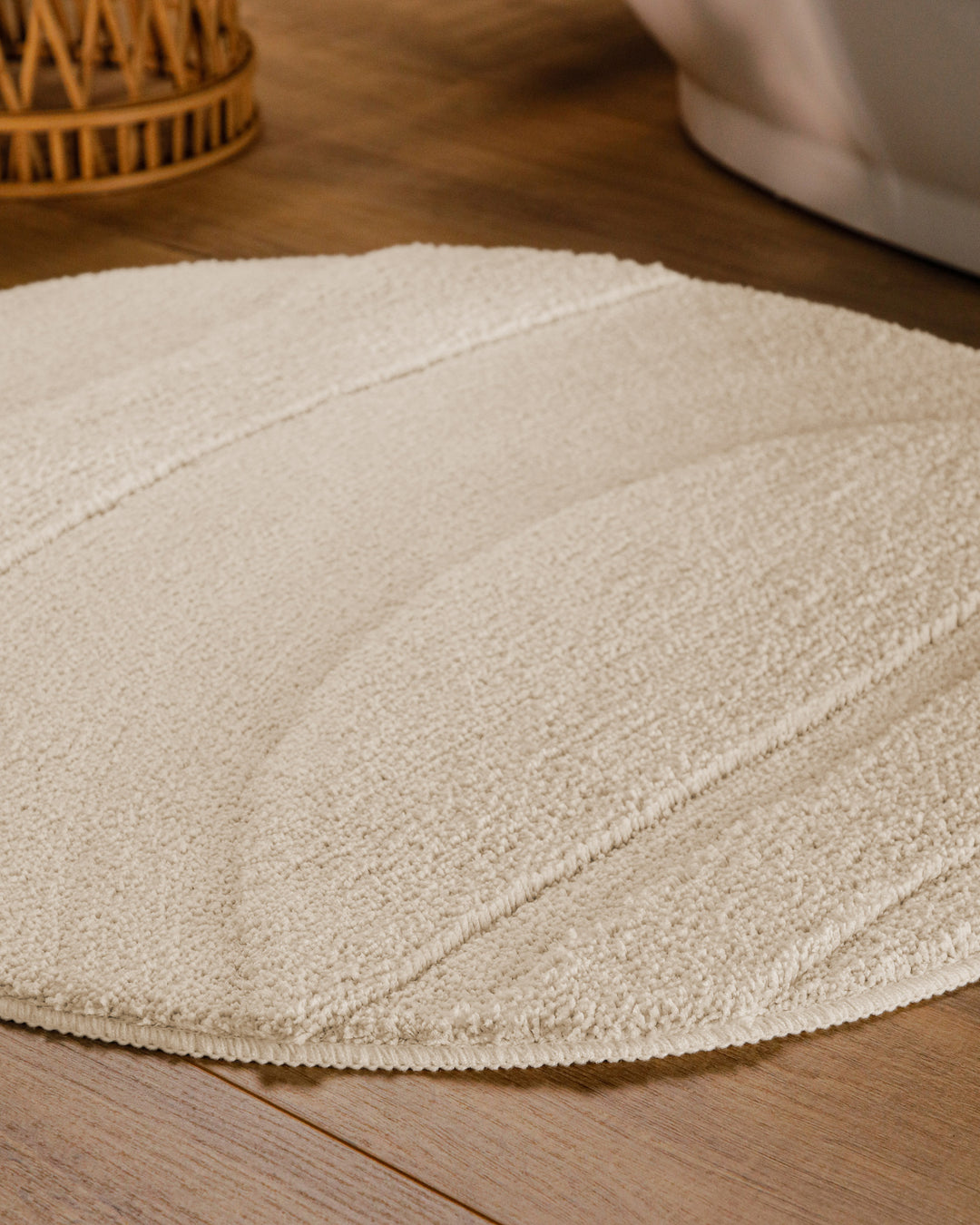 Badteppich Marc Creme Weiß rund im Badezimmer auf Holzboden neben Badewanne, Florstruktur und Linienrelief erkennbar