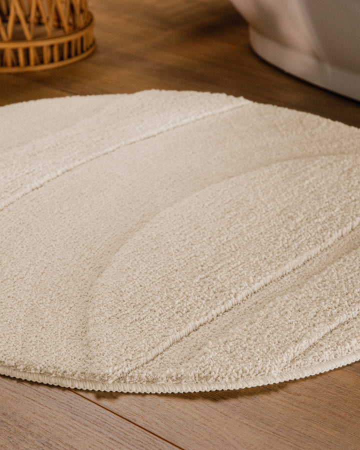 Badteppich Marc Creme Weiß rund im Badezimmer auf Holzboden neben Badewanne, Florstruktur und Linienrelief erkennbar