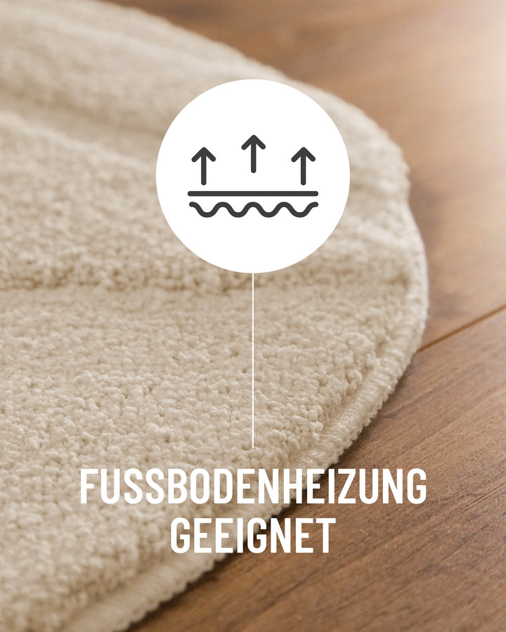 Badteppich Marc Creme Weiß Detail der Teppichkante auf Holzboden, Symbol weist auf Eignung für Fußbodenheizung hin