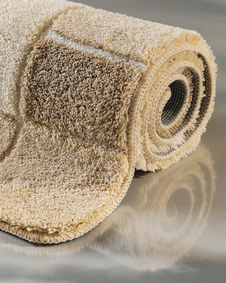 Badteppich Villa Elba in Creme-Beige aufgerollt in Nahaufnahme – Querschnitt zeigt die Flordicke beider Zonen und die textile Rückenstruktur
