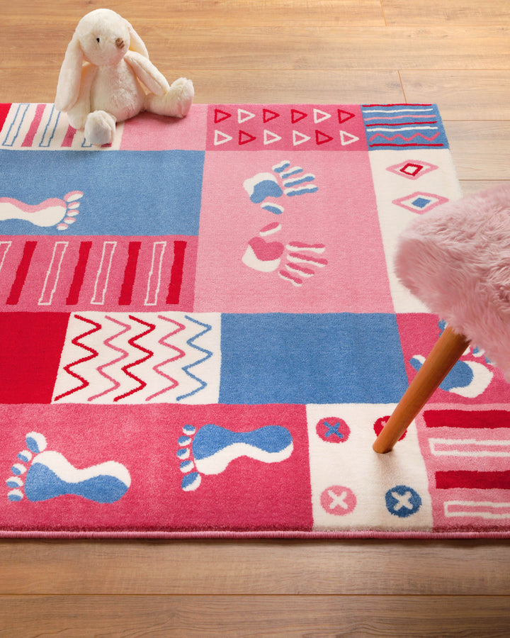 Nahaufnahme des Kinderteppichs Hand&Feet mit blauem und pinkem Fußabdruck-Motiv auf hellem Untergrund