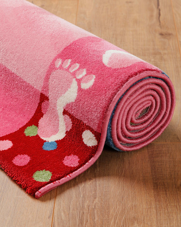 Aufgerollter Kinderteppich Hand&Feet in Rosa mit gepunktetem Rand und Fußabdruck-Muster