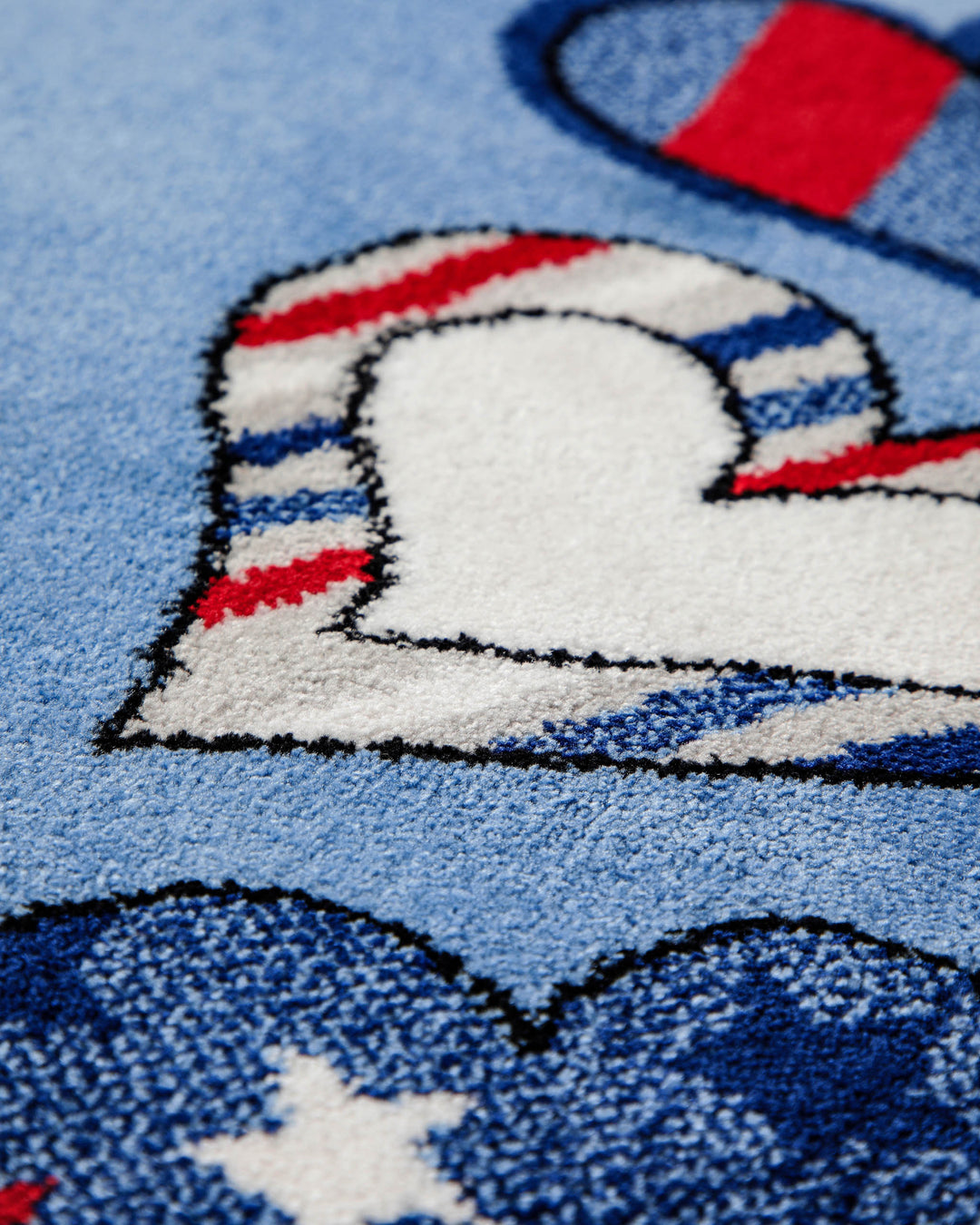 Detailaufnahme des Randmusters vom Kinderteppich Just Hearts mit großem weißem Herz auf blauem Untergrund, umgeben von Sternen