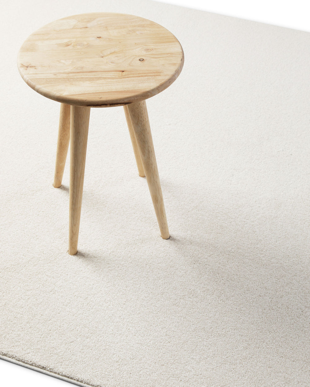 Kurzflor Teppich Freja Creme Weiß im Wohnraum mit Hocker, zeigt helle und ruhige Farbwirkung