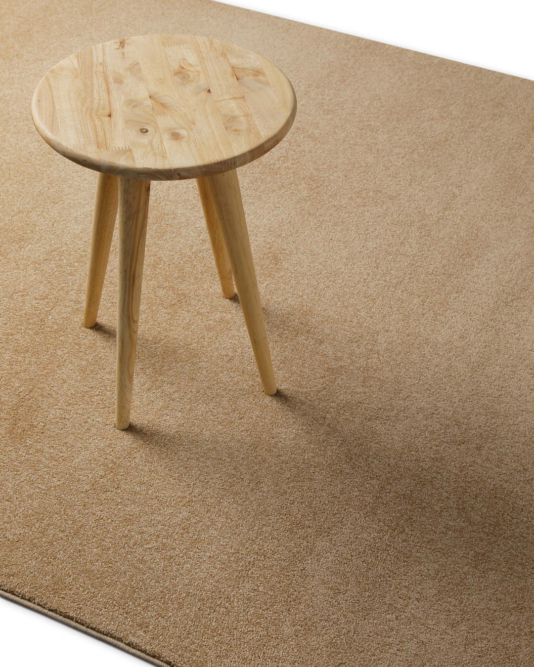 Kurzflor Teppich Freja Sand Beige im Wohnraum mit Hocker, zeigt warme und natürliche Farbwirkung