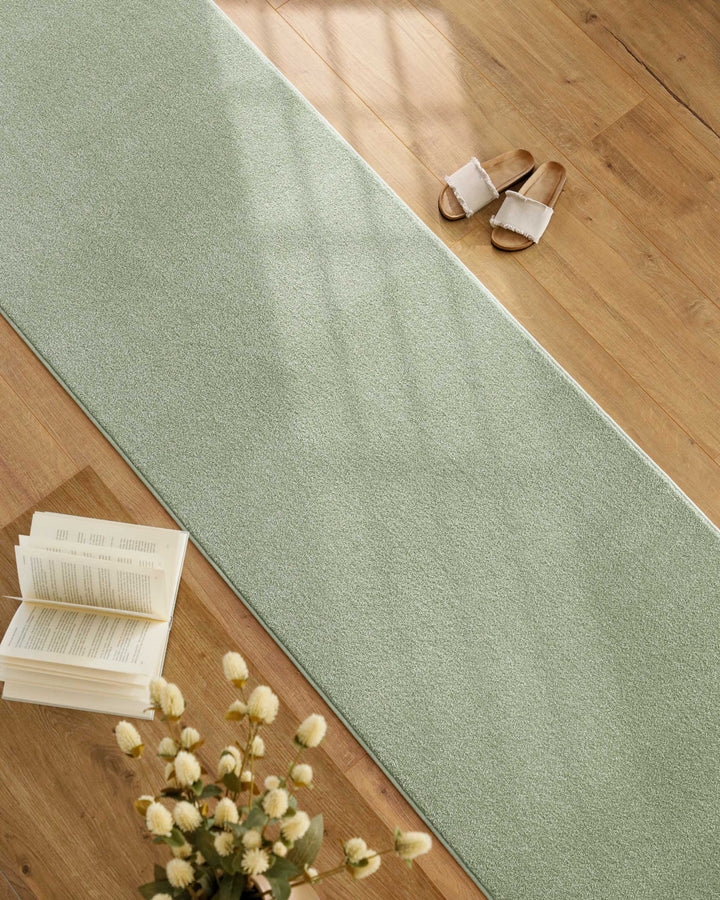 Kurzflor Teppich Läufer Vegas Hellgrün im Wohnraum entlang Möbeln auf Holzboden, lange schmale Form sichtbar