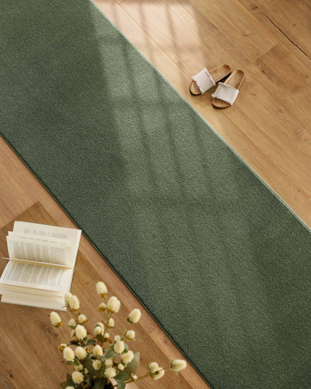 Kurzflor Teppich Läufer Vegas Grün im Wohnraum entlang Möbeln auf Holzboden, lange schmale Form mit ruhiger Oberfläche