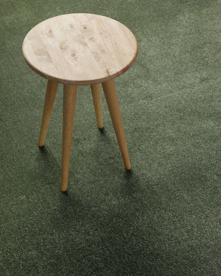 Kurzflor Teppich Montepulciano Laub Grün im Wohnraum mit Hocker