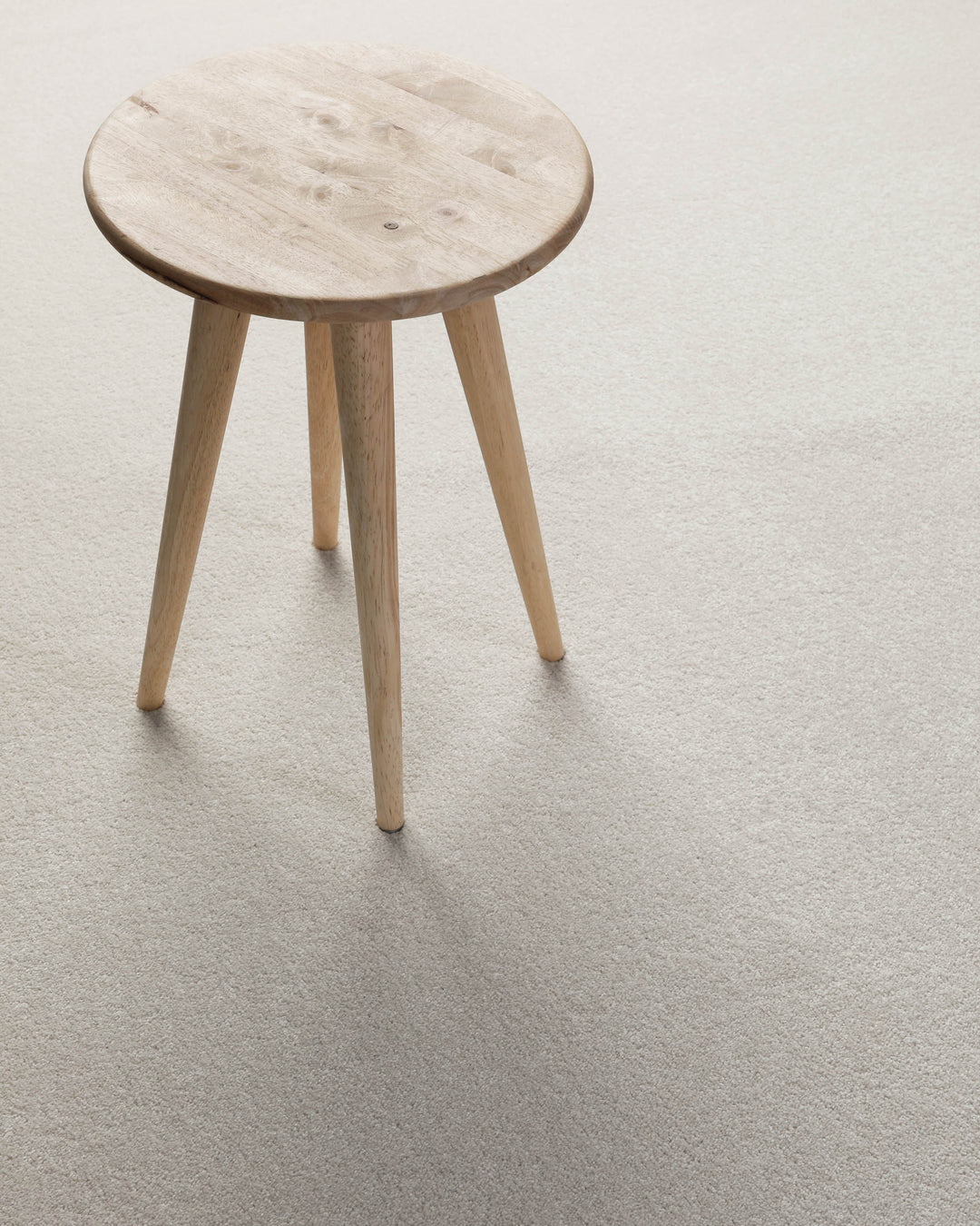 Kurzflor Teppich Montepulciano Creme Weiß im Wohnraum mit Hocker auf heller Oberfläche