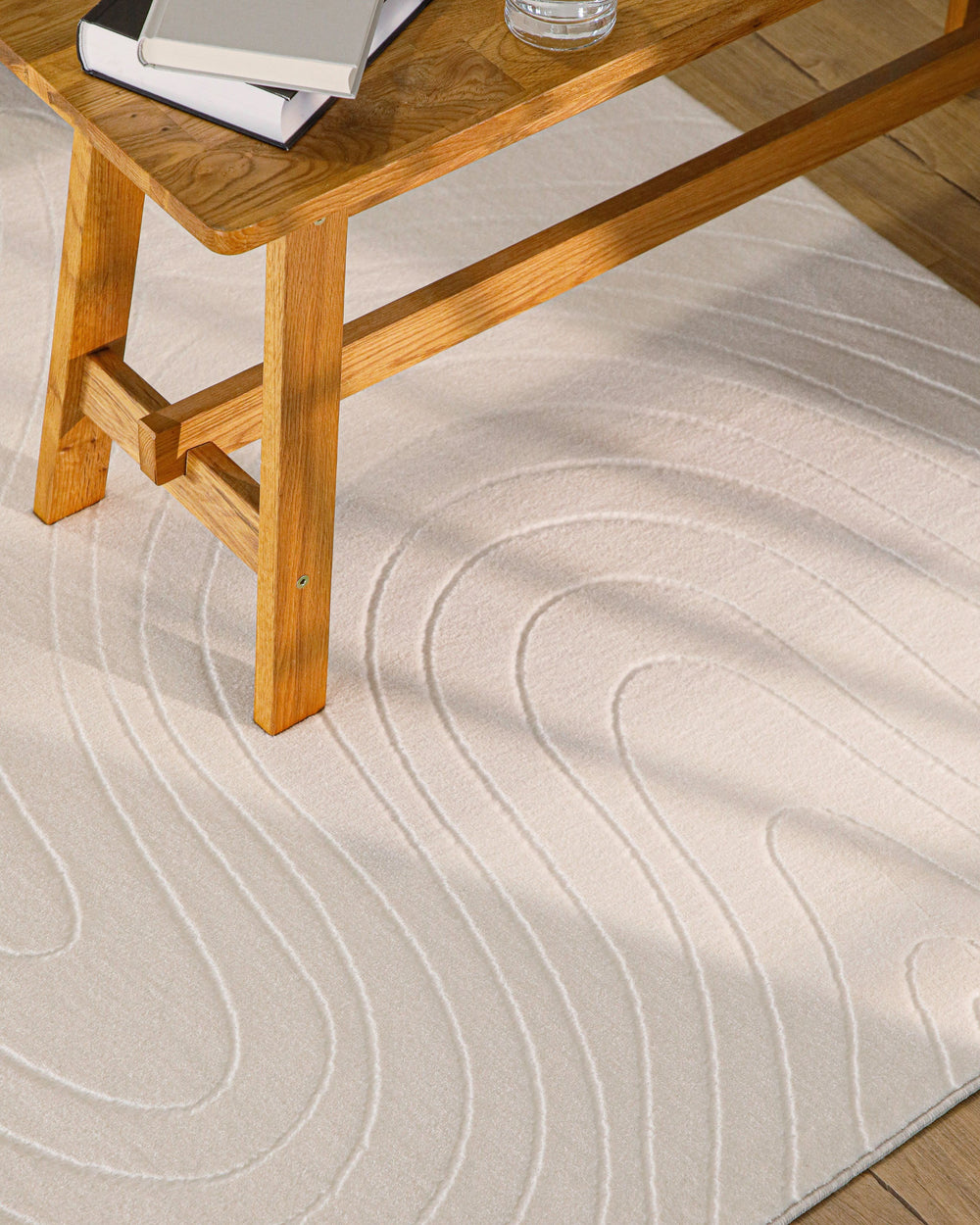 Nuuk Flow Teppich creme-weiß unter Holztisch mit Reliefmuster