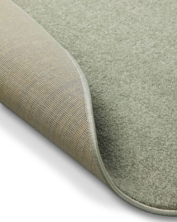 Kurzflor Teppich Freja Licht Grün rund Detail der umgelegten Ecke, Rückseite sichtbar