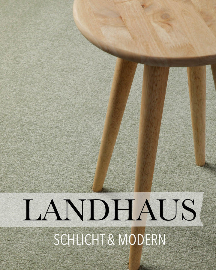 Kurzflor Teppich Freja Licht Grün rund im Wohnraum mit Schriftzug Landhaus, zeigt gemütliche Raumwirkung