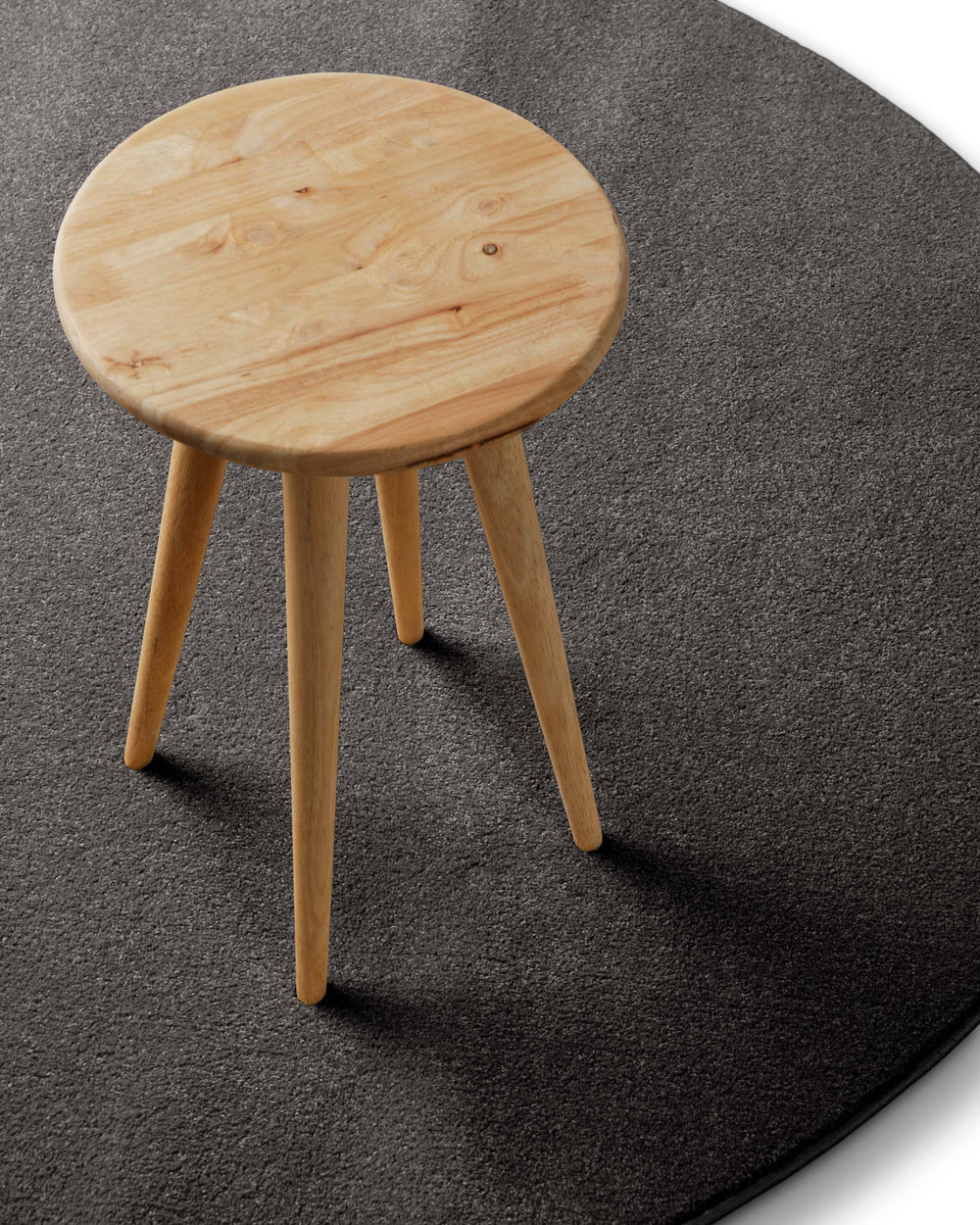 Im Raum platziert mit Hocker zeigt der Teppich eine ruhige, moderne Wirkung mit leicht melierter Struktur