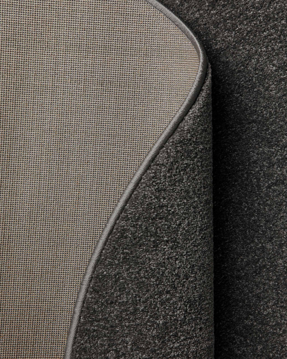 Kurzflor Teppich Montepulciano Anthrazit Grau rund, Rückseite sichtbar mit Jute-Träger und umgelegter Ecke