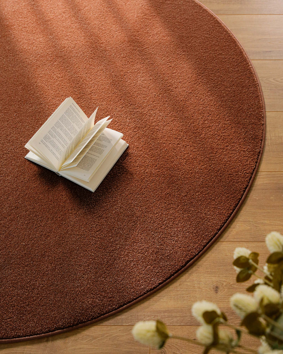 Kurzflor Teppich Vegas Rot rund Nahaufnahme mit Buch auf der Fläche, gleichmäßige Struktur erkennbar